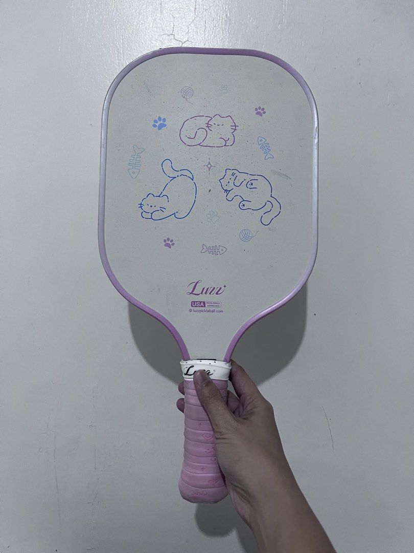 Luzz Pickleball Paddle Set with Case and Balls (Category: Racket and Ball Sports) located in Cotabato. Submitted by goodbyethings09 (Listing ID 1470703717, Image 1). Description: - Adorable Luzz pickleball paddle with cute cat face graphics - Comfortable pink grip tape wrapped handle - USA Pickleball approved for official play - Includes matching carrying case and 4 pickleballs (green, pink, and purple) - Condition: Minor dirt marks on the white 