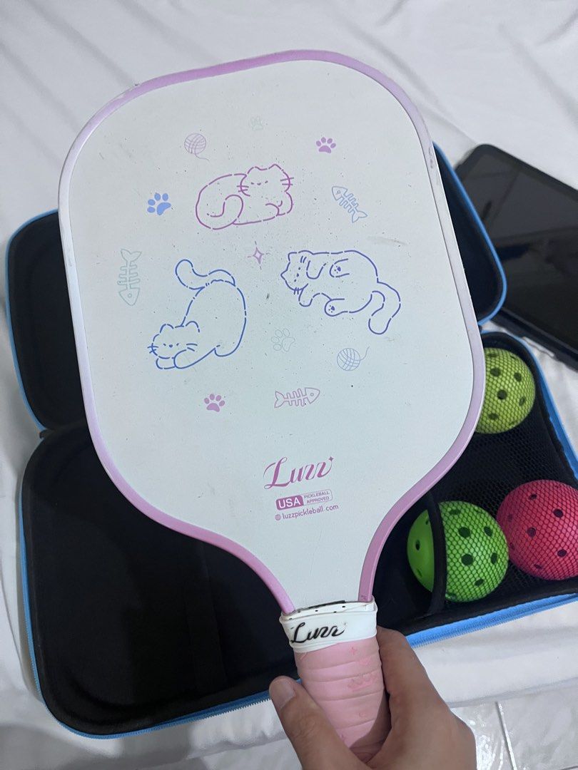 Luzz Pickleball Paddle Set with Case and Balls (Category: Racket and Ball Sports) located in Cotabato. Submitted by goodbyethings09 (Listing ID 1470703717, Image 3). Description: - Adorable Luzz pickleball paddle with cute cat face graphics - Comfortable pink grip tape wrapped handle - USA Pickleball approved for official play - Includes matching carrying case and 4 pickleballs (green, pink, and purple) - Condition: Minor dirt marks on the white 