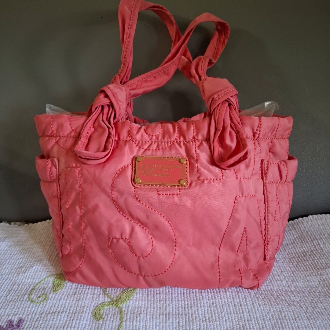 Marc by Marc Jacobs Pink Quilted Tote Bag (Category: Luxury Bags & Wallets) located in Don Carlos. Submitted by PphiXi_Finds (Listing ID 1470727108, Image 1). Description: - Brand: Marc by Marc Jacobs - Material: Bright pink quilted nylon with black and white monogram lining - Design: Bold exterior logo stitching with signature front plaque - Handles: Double knotted shoulder handles for a chic look - Storage: Convenient interior zip pocket and sl