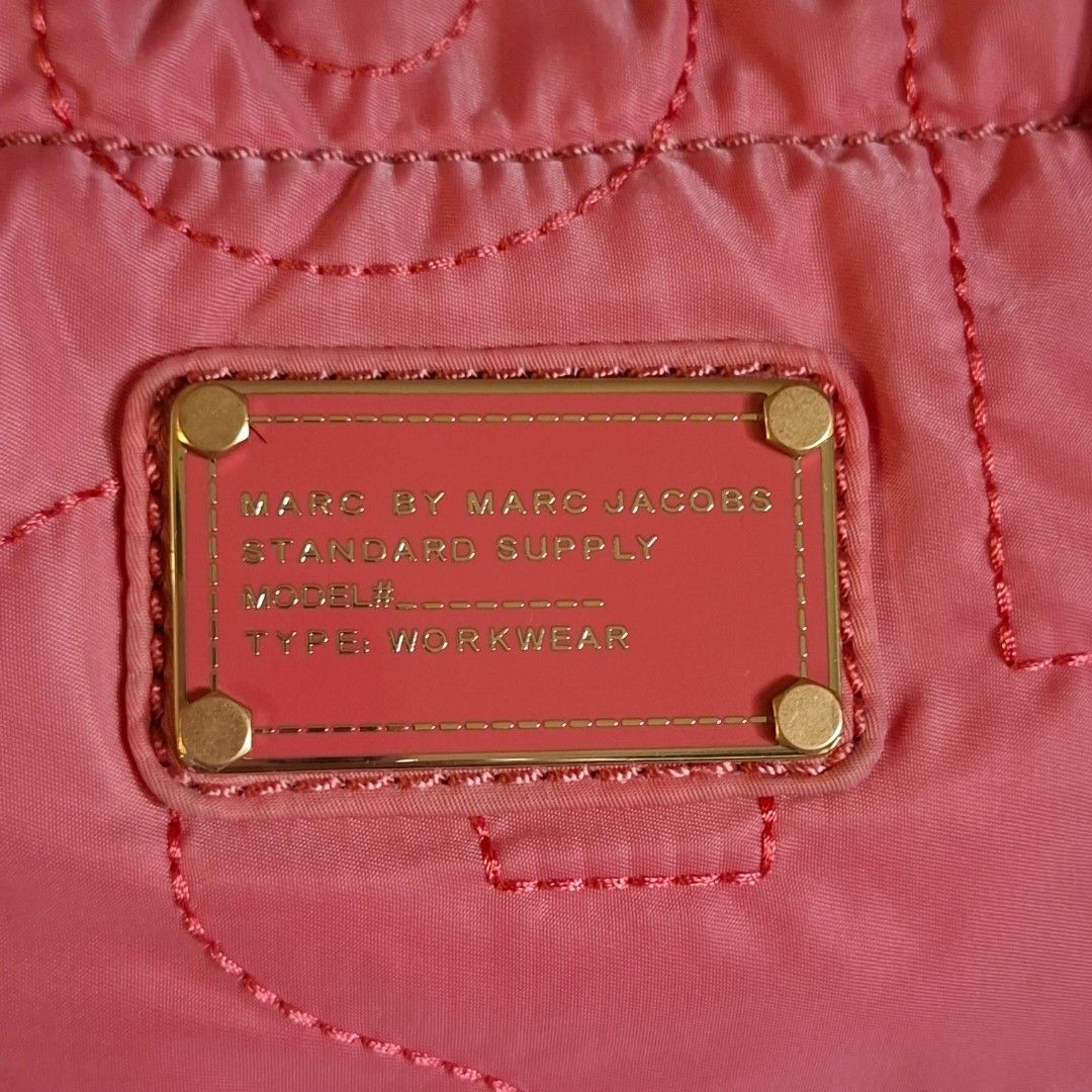 Marc by Marc Jacobs Pink Quilted Tote Bag (Category: Luxury Bags & Wallets) located in Don Carlos. Submitted by PphiXi_Finds (Listing ID 1470727108, Image 3). Description: - Brand: Marc by Marc Jacobs - Material: Bright pink quilted nylon with black and white monogram lining - Design: Bold exterior logo stitching with signature front plaque - Handles: Double knotted shoulder handles for a chic look - Storage: Convenient interior zip pocket and sl