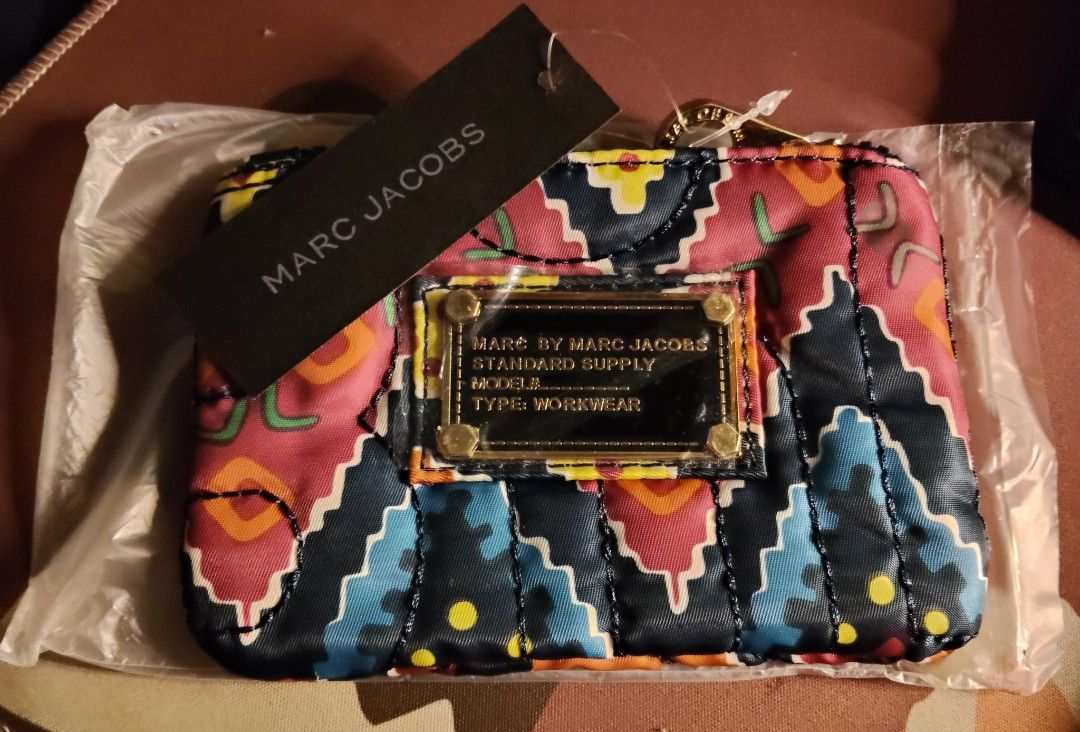 Marc by Marc Jacobs purse (Category: Luxury Bags & Wallets) located in Quirino. Submitted by megay12 (Listing ID 1470693044, Image 1). Description: - Brand: Marc by Marc Jacobs - Condition: Brand new, never removed from original plastic packaging - Design: Vibrant geometric pattern in pink, blue, orange, and black with gold-tone hardware - Interior: Classic black and white brand logo fabric lining - Extras: Includes attached black hang tag - Perf