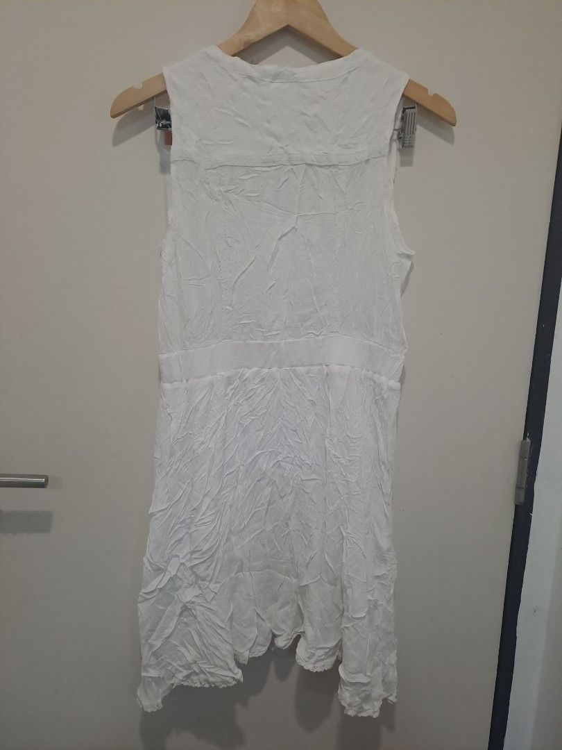 Maurices white dress (Category: Dresses) located in Manila. Submitted by joanbalde39643 (Listing ID 1470661358, Image 3). Description: This is a sleeveless white casual dress featuring a distinctive V-neckline framed by ornate crochet-style lace paneling. It is designed with a defined waistband and a lightweight, crinkled fabric texture throughout the skirt section, giving it an effortless, bohemian-inspired look perfect for summer or resort wear