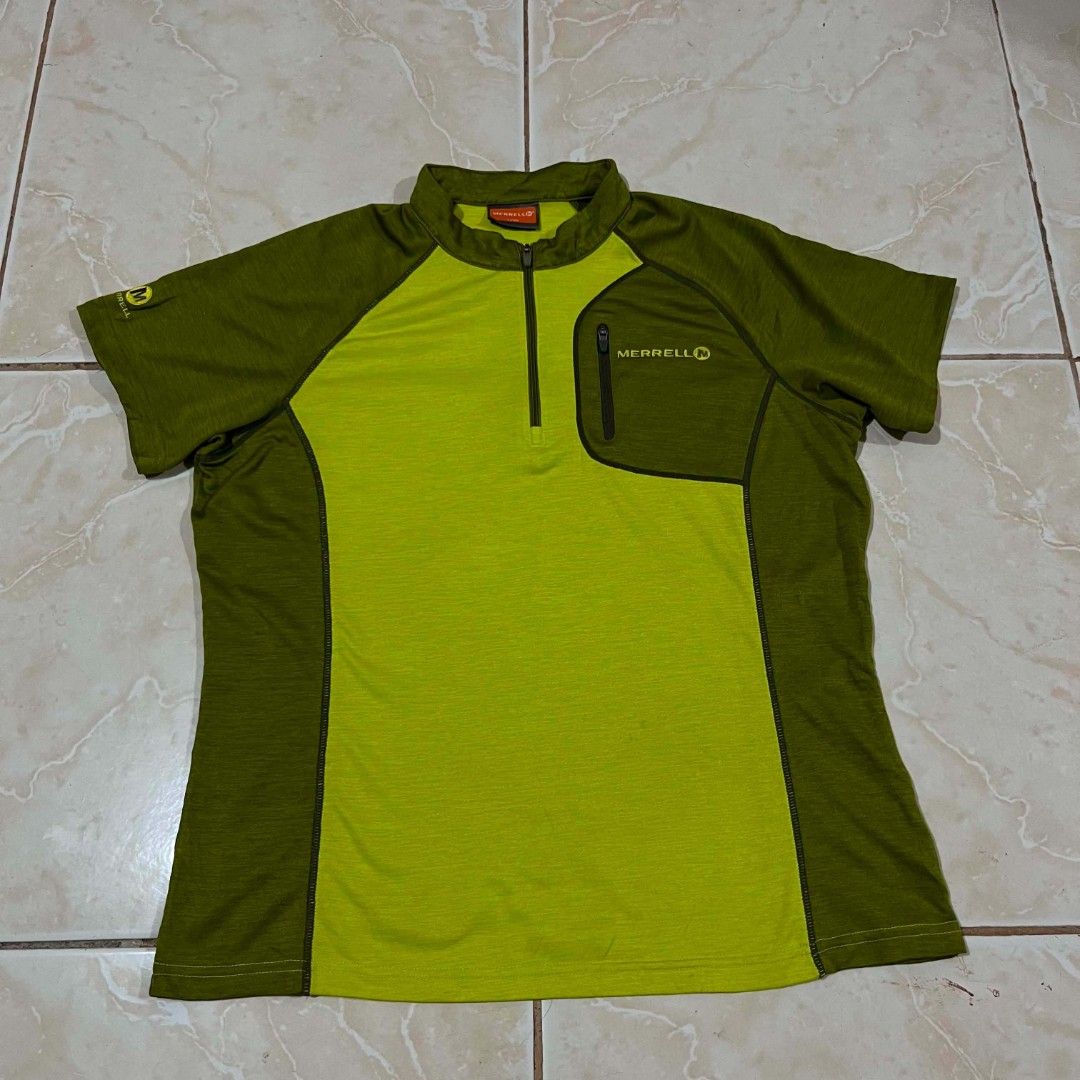 Merrell Green Short Sleeve Zip Shirt (Category: Activewear) located in El Salvador. Submitted by pretiezt2001 (Listing ID 1470639745, Image 1). Description: - Brand: Merrell - Color: Olive green with lime green accents - Style: Half-zip front with a small zipped chest pocket and short sleeves - Material: Lightweight and breathable fabric - Ideal For: Hiking, cycling, and other outdoor activities - Condition: Great, clean condition with no obvious