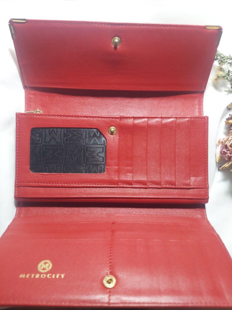 Metrocity Red Leather Long Wallet (Category: Wallets & Card holders) located in Quezon City. Submitted by never_a_clutter (Listing ID 1470591419, Image 2). Description: - Brand: Metrocity - Color: Bright red with gold hardware details - Material: Genuine leather - Closure: Secure snap button - Interior: Multiple card slots, ID window, long slip compartments, and zippered coin pocket - Lining: Signature Metrocity monogram pattern - Condition: 9/10