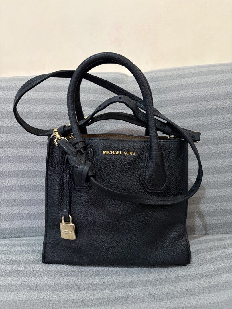 Michael Kors Black Leather Handbag with Lock Charm (Category: Luxury Bags & Wallets) located in Pasig City. Submitted by mau_llamas (Listing ID 1470688151, Image 1). Description: - Brand: Michael Kors - Material: Premium black pebble leather with elegant gold hardware - Versatility: Includes top handles and a detachable shoulder strap for crossbody wear - Interior: Clean lined interior featuring a secure zip pocket - Details: Chic hanging padlock