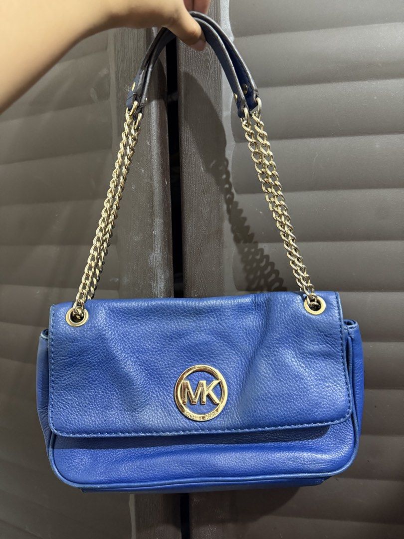 Michael Kors Blue Leather Shoulder Bag (Category: Shoulder Bags) located in Rizal. Submitted by lovegclothingph (Listing ID 1470673580, Image 1). Description: - Brand: Michael Kors - Material: Genuine leather in a bright blue shade - Hardware: Gold-tone with signature MK circular logo - Straps: Combination of chain and leather - Closure: Front flap - Compartments: Exterior back slip pocket - Condition: Good, with minor scuffs on the metal logo an