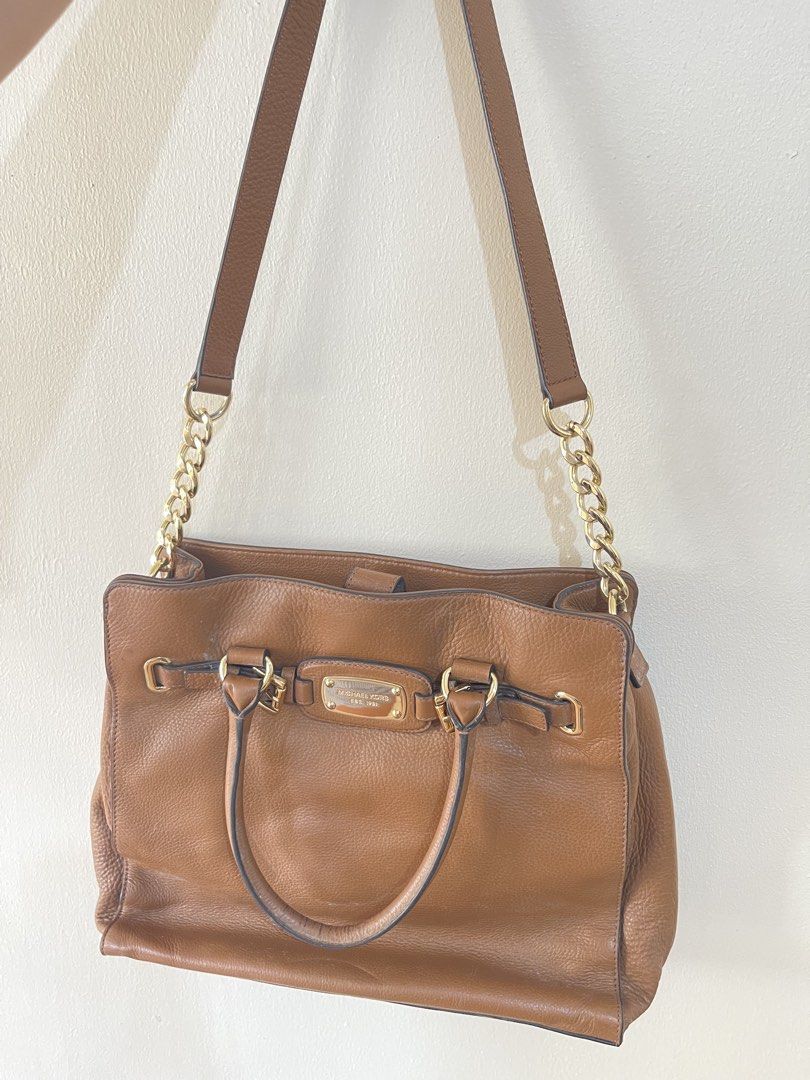 Michael Kors Brown Leather Shoulder Bag Tote (Category: Luxury Bags & Wallets) located in Quezon City. Submitted by mvaldez (Listing ID 1470587395, Image 1). Description: - Brand: Michael Kors - Material: Premium brown leather with gold-tone hardware - Straps: Dual top handles and stylish chain shoulder strap - Interior: Signature Michael Kors monogram fabric lining - Compartments: Center zip divider, plus convenient slip and zip side pockets - C