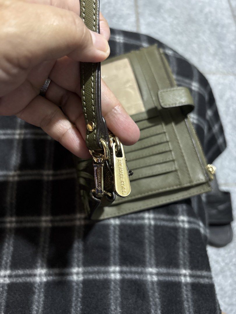 Michael Kors Leaf Print Wristlet Wallet (Category: Wallets & Card holders) located in Las Pinas. Submitted by pamboi (Listing ID 1470570210, Image 3). Description: - Brand: Michael Kors - Design: Brown and green leaf print with gold-tone hardware - Interior: Olive green leather with multiple card slots and ID window - Closure: Secure snap closure and dual zippered compartments - Extras: Includes removable wrist strap - Condition: Clean inside and