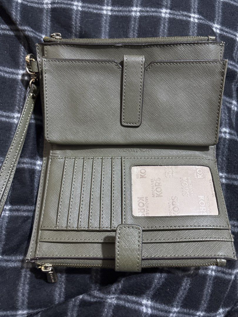 Michael Kors Leaf Print Wristlet Wallet (Category: Wallets & Card holders) located in Las Pinas. Submitted by pamboi (Listing ID 1470570210, Image 2). Description: - Brand: Michael Kors - Design: Brown and green leaf print with gold-tone hardware - Interior: Olive green leather with multiple card slots and ID window - Closure: Secure snap closure and dual zippered compartments - Extras: Includes removable wrist strap - Condition: Clean inside and
