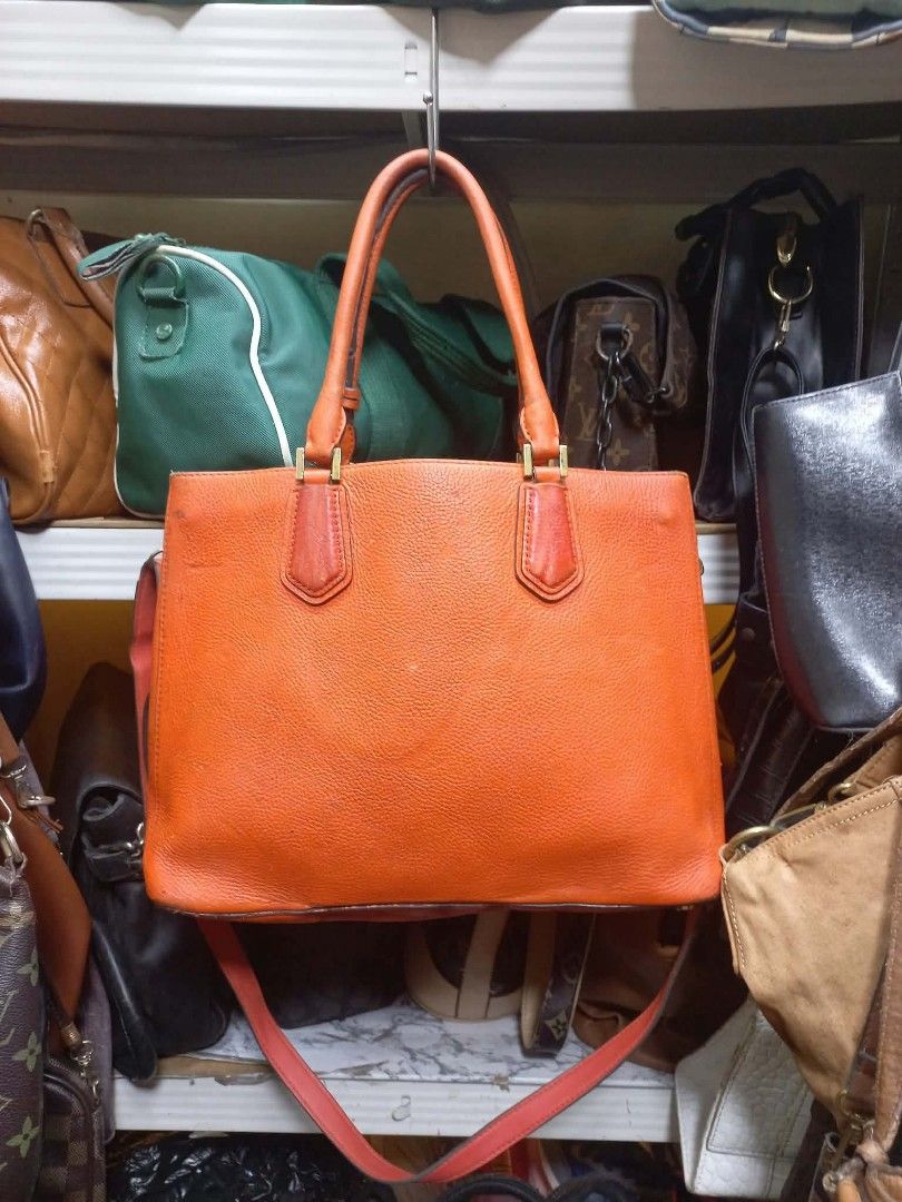 Michael Kors Orange Leather Tote Bag (Category: Tote Bags) located in Manila. Submitted by del_thrifts03 (Listing ID 1470727321, Image 2). Description: - Brand: Michael Kors - Material: Pebble leather in bright orange - Hardware: Gold-tone, featuring front logo lettering and a hanging padlock charm - Straps: Dual top handles and a detachable shoulder strap - Interior: Spacious main compartment with metal brand plaque - Condition: Excellent.