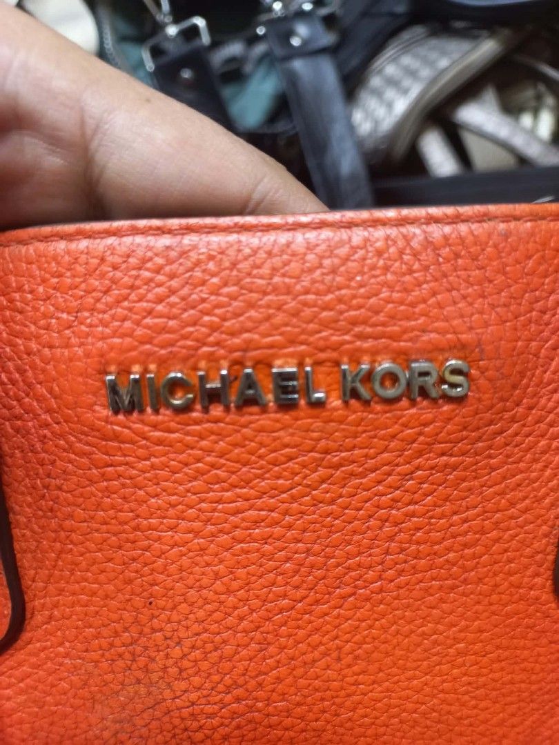 Michael Kors Orange Leather Tote Bag (Category: Tote Bags) located in Manila. Submitted by del_thrifts03 (Listing ID 1470727321, Image 3). Description: - Brand: Michael Kors - Material: Pebble leather in bright orange - Hardware: Gold-tone, featuring front logo lettering and a hanging padlock charm - Straps: Dual top handles and a detachable shoulder strap - Interior: Spacious main compartment with metal brand plaque - Condition: Excellent.
