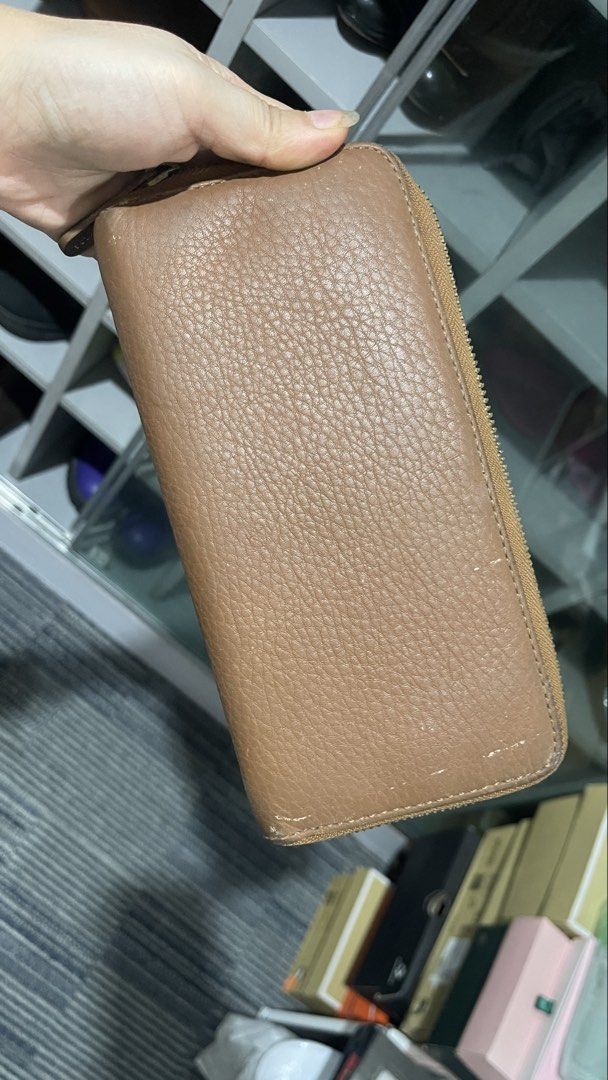 Michael Kors Tan Leather Zip Around Wallet (Category: Wallets & Card holders) located in Rizal. Submitted by annelimited_stuffs (Listing ID 1470669699, Image 2). Description: Tan pebble leather Michael Kors zip around wallet with gold tone hardware and logo plaque. Multiple card slots, slip pockets, and a central zippered coin compartment inside. Interior fabric features monogram print. Some minor wear on the exterior corners and metal plate..