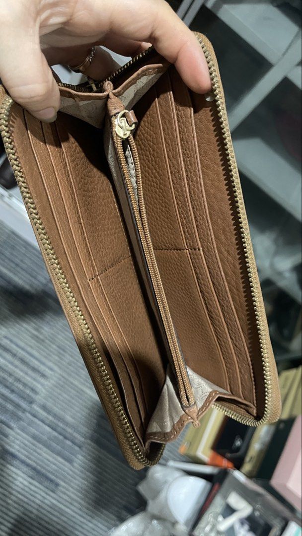 Michael Kors Tan Leather Zip Around Wallet (Category: Wallets & Card holders) located in Rizal. Submitted by annelimited_stuffs (Listing ID 1470669699, Image 3). Description: Tan pebble leather Michael Kors zip around wallet with gold tone hardware and logo plaque. Multiple card slots, slip pockets, and a central zippered coin compartment inside. Interior fabric features monogram print. Some minor wear on the exterior corners and metal plate..