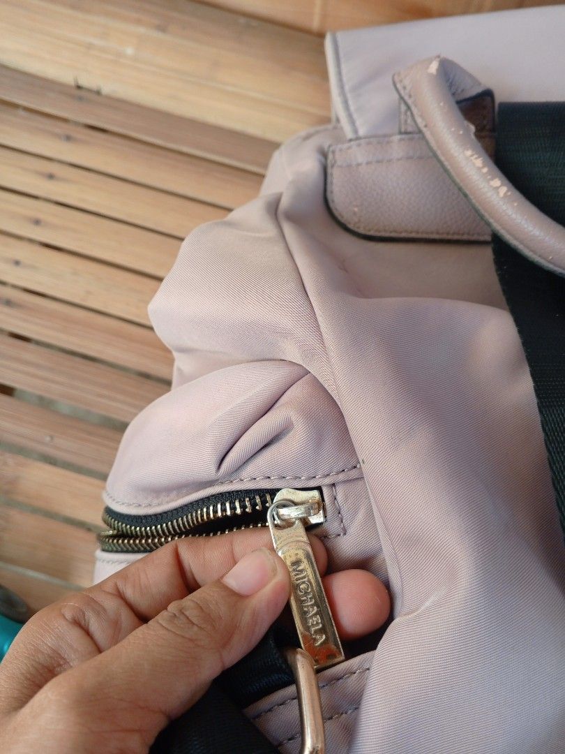 MICHAELA Dusty Pink Backpack with Front Pocket (Category: Backpacks) located in Binmaley. Submitted by ezekislacl02490 (Listing ID 1470591951, Image 3). Description: - Brand: MICHAELA - Color: Dusty pink with black adjustable straps and gold-toned hardware - Material: Nylon body with faux leather flap and trim - Compartments: Multiple zippered pockets on the front and sides - Condition: Fair; minor faux leather peeling on the top handle and botto