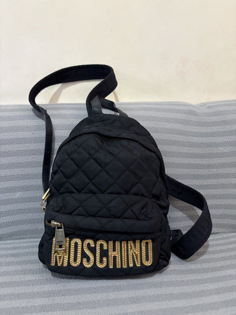 Moschino Quilted Nylon Backpack with Gold Logo (Category: Backpacks) located in Pasig City. Submitted by mau_llamas (Listing ID 1470678423, Image 1). Description: - Moschino black quilted nylon backpack - Eye-catching metallic gold Moschino lettering on the front pocket - Luxurious gold-tone hardware and zippers throughout - Comfortable adjustable black straps - Front zipped compartment for easy access to small essentials - Black fabric-lined int