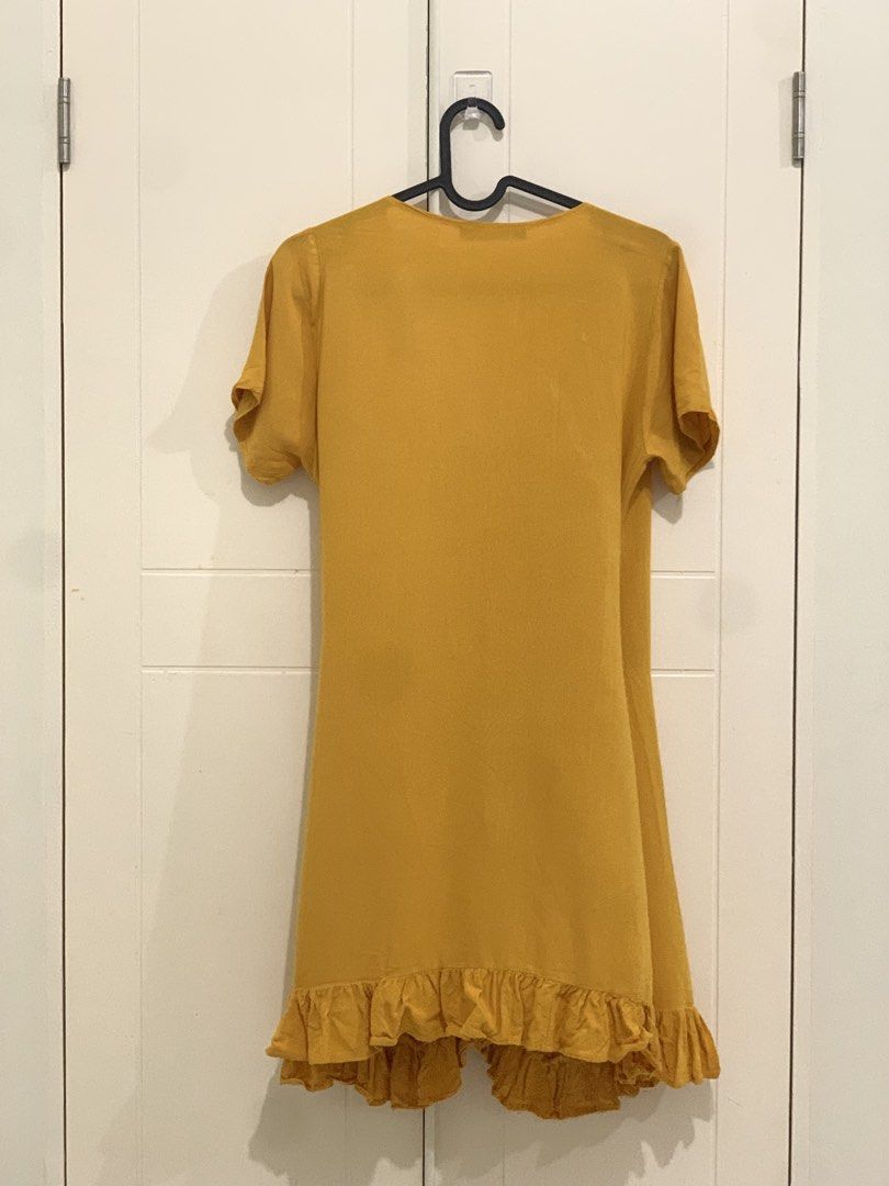 Mustard Yellow Wrap Dress with Ruffles (Category: Dresses) located in Pasig City. Submitted by lovedbyri (Listing ID 1470639636, Image 2). Description: - Color: Mustard Yellow - Style: Wrap dress with V-neck and short sleeves - Details: Self-tie waist and playful ruffles along the hem and wrap edge - Length: Hits above the knee - Fabric: Lightweight and breathable, perfect for warm days - Condition: Clean and ready to wear.
