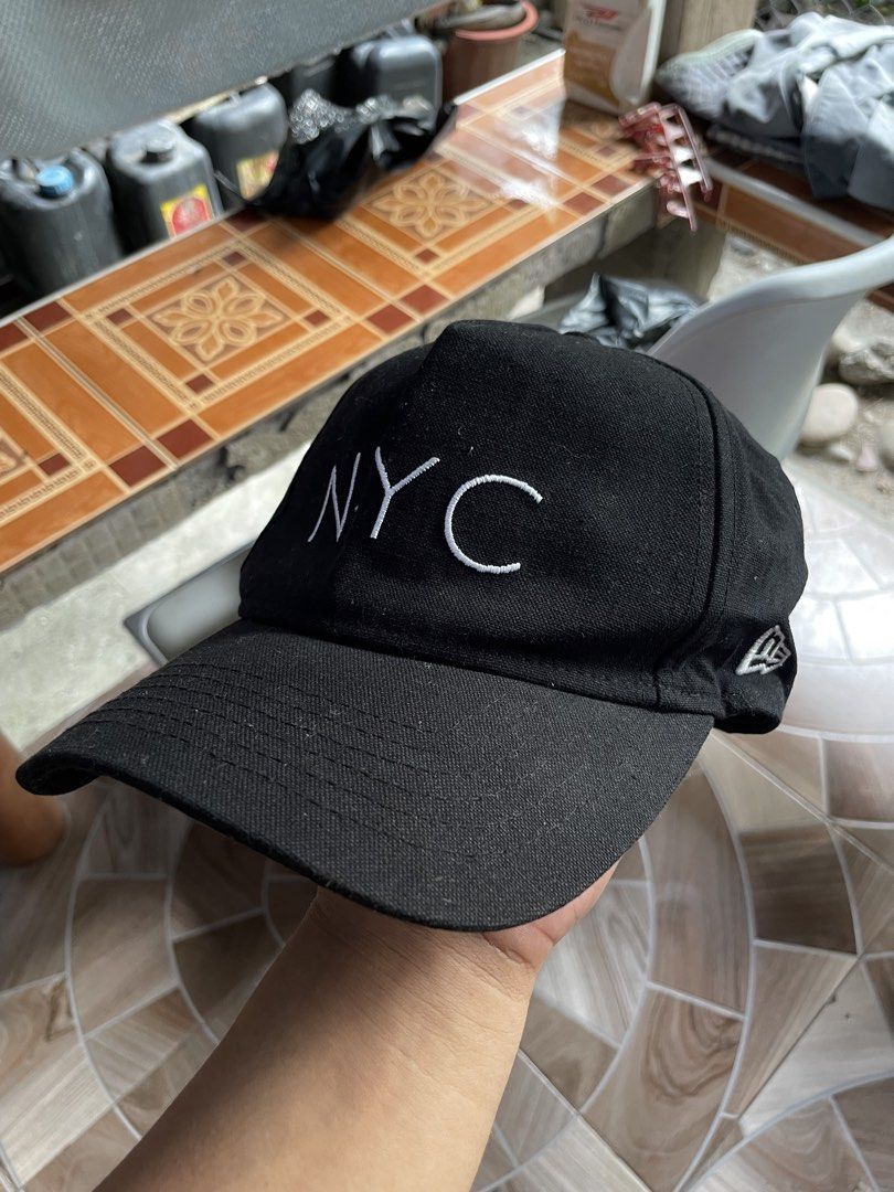 New Era NYC Black Cap Medium/Large (Category: Caps & Hats) located in Manila. Submitted by deadstock2025 (Listing ID 1470688388, Image 2). Description: - Brand: New Era - Color: Black with white 'NYC' embroidery - Style: Classic unstructured dad hat with curved brim - Size: Medium/Large (adjustable metal strap closure) - Material: 100% cotton - Condition: Clean inside and out, ready to wear.