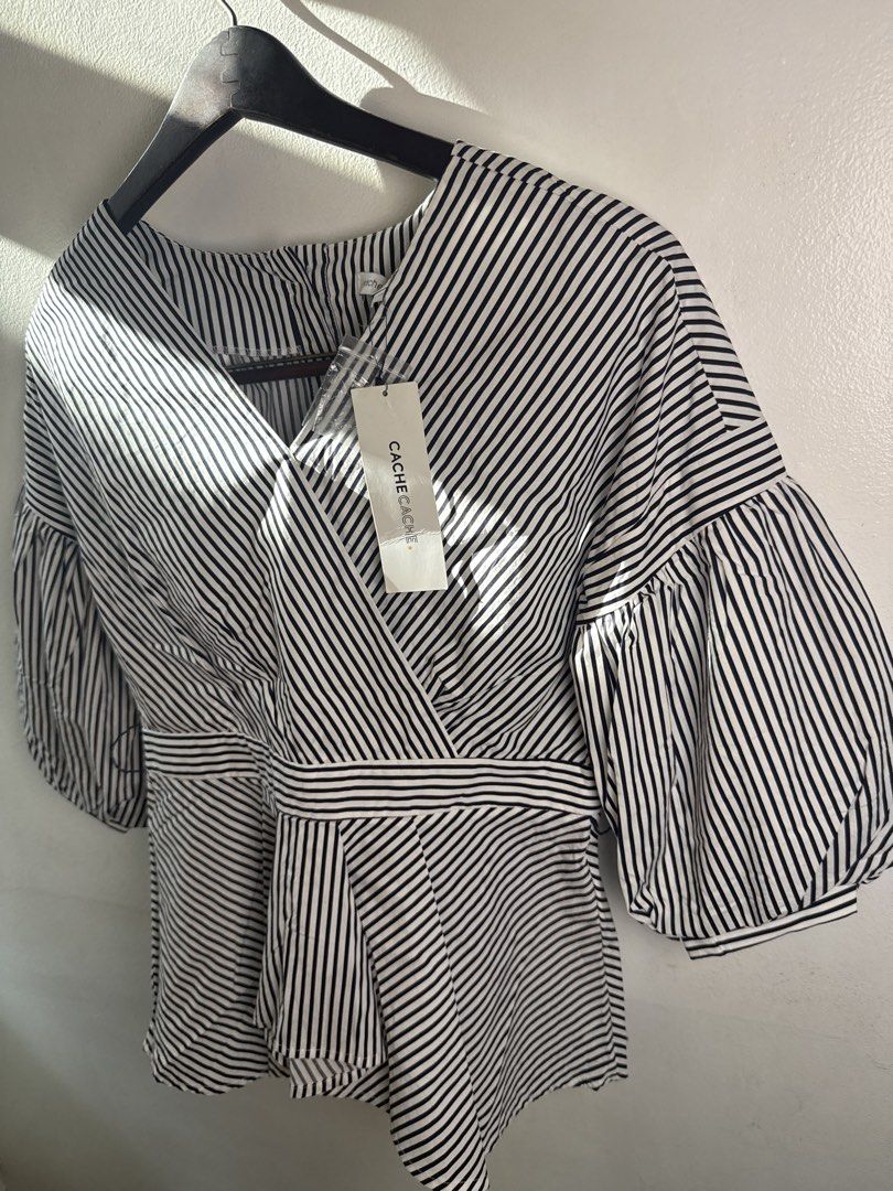 New w tags Cache Cache Black and White Striped Blouse (Category: Blouses) located in Quezon City. Submitted by dropdeadprices (Listing ID 1470620544, Image 2). Description: - Brand: Cache Cache (With tag attached, never worn) - Material: 100% breathable cotton - Design: Classic black and white stripes with a V-neck wrap front Issue: missing belt - Sleeves: Stylish voluminous balloon sleeves - Fit: Flattering fitted waist with a flared peplum hem 