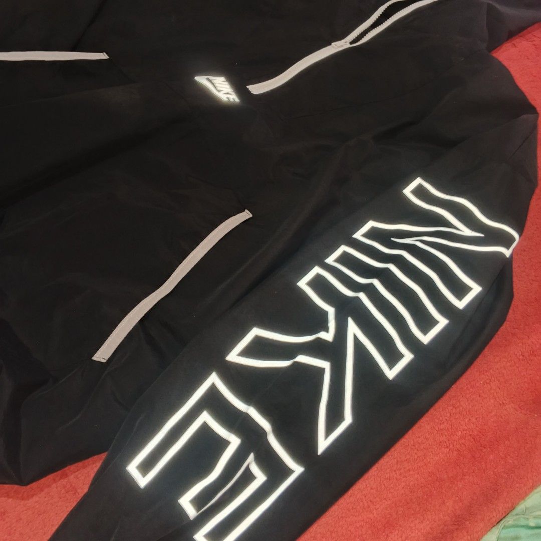 Nike Black Half-Zip Windbreaker Hoodie Jacket (Category: Coats, Jackets and Outerwear) located in Manila. Submitted by beveragedj77 (Listing ID 1470618745, Image 3). Description: - Color: Black - Style: Half-zip windbreaker with matching hood and adjustable drawstrings - Branding: Large white Nike logo on the left sleeve and small Nike swoosh centered above the front pocket - Pockets: Front kangaroo pocket with stylish reflective grey piping - Ma