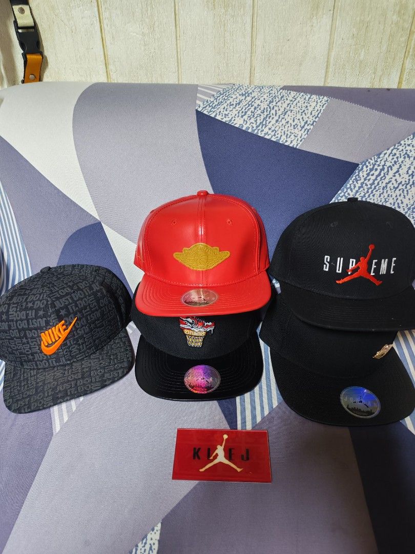 Nike Jordan and Supreme Snapback Hats Bundle (Category: Caps & Hats) located in Manila. Submitted by klej26 (Listing ID 1470658988, Image 1). Description: Collection of snapback caps including Nike, Air Jordan, and Supreme designs. Various colors and styles like red leather finish, black with embroidery, and patterned grey. All have flat brims and stickers on the bill. Great streetwear accessories for daily wear or collecting..