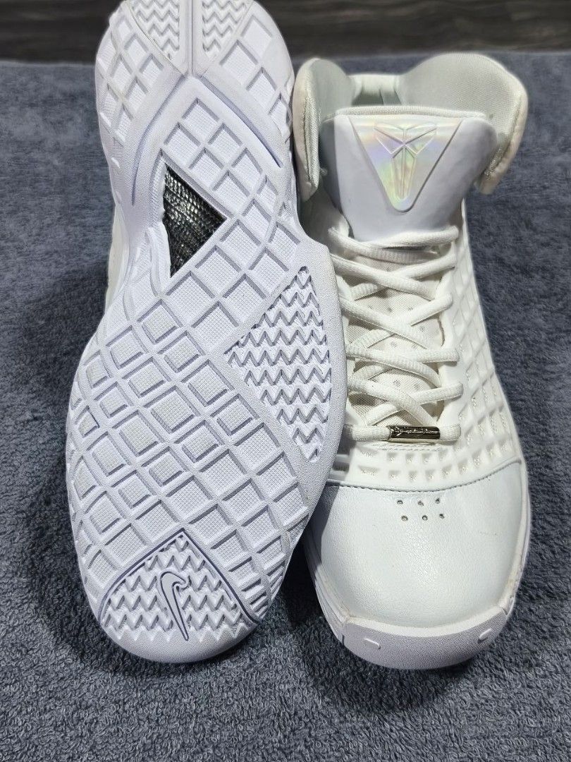 Nike Kobe 1 Protro White Sneaker (Category: Sneakers) located in Manila. Submitted by kikocastro37272 (Listing ID 1470693514, Image 2). Description: - Model: Nike Kobe 1 Protro Basketball Sneakers - Colorway: Clean White aesthetic - Design: High-top silhouette with a distinctive grid cage upper pattern - Branding: Holographic tongue logo with signature sheath emblem and metallic silver heel Swoosh - Details: Metallic silver lace aglets and textur