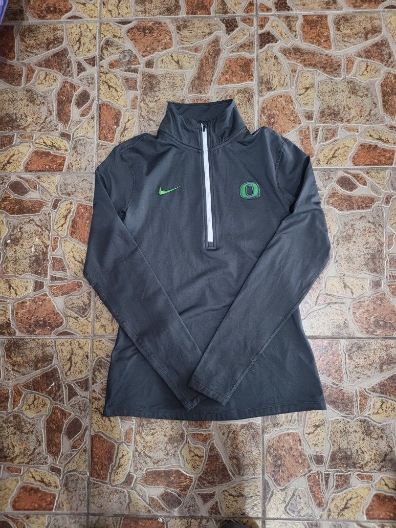 Nike Oregon Ducks Dri-Fit 1/4 Zip Pullover (Category: Coats, Jackets and Outerwear) located in Bayombong. Submitted by onlygoodfinds. (Listing ID 1470634223, Image 2). Description: - Brand: Nike - Team: Oregon Ducks - Color: Charcoal grey with white zipper - Logos: Green Nike swoosh on right chest, green Oregon 'O' on left - Material: Nike Dri-Fit (lightweight and comfortable) - Size: Large - Condition: Excellent, pre-loved - Perfect for workouts