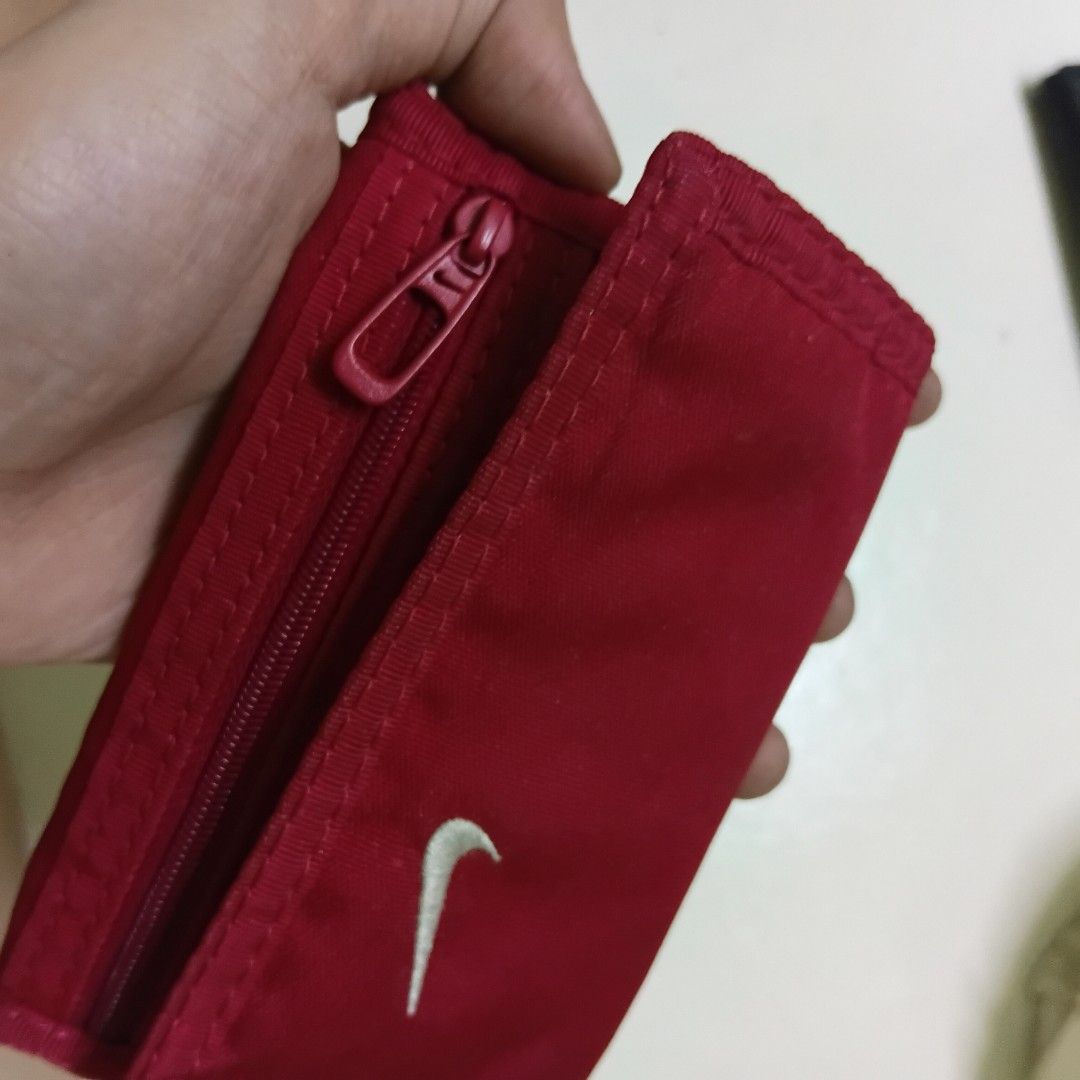 Nike Red Tri-fold Wallet (Category: Wallets & Card holders) located in Manila. Submitted by daphnefinds (Listing ID 1470641341, Image 2). Description: - Brand: Nike - Color: Red with white embroidered swoosh - Material: 100% polyester body, 100% nylon lining - Closure: Secure hook-and-loop (Velcro) - Features: Zippered pocket and multiple interior card slots - Origin: Made in China - Condition: Brand new / Excellent quality.