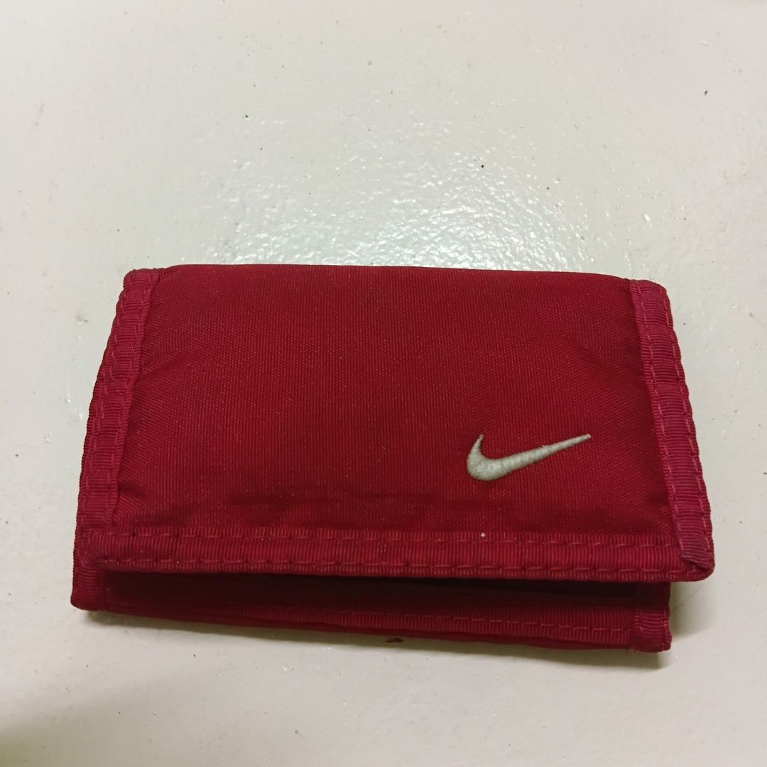 Nike Red Tri-fold Wallet (Category: Wallets & Card holders) located in Manila. Submitted by daphnefinds (Listing ID 1470641341, Image 1). Description: - Brand: Nike - Color: Red with white embroidered swoosh - Material: 100% polyester body, 100% nylon lining - Closure: Secure hook-and-loop (Velcro) - Features: Zippered pocket and multiple interior card slots - Origin: Made in China - Condition: Brand new / Excellent quality.