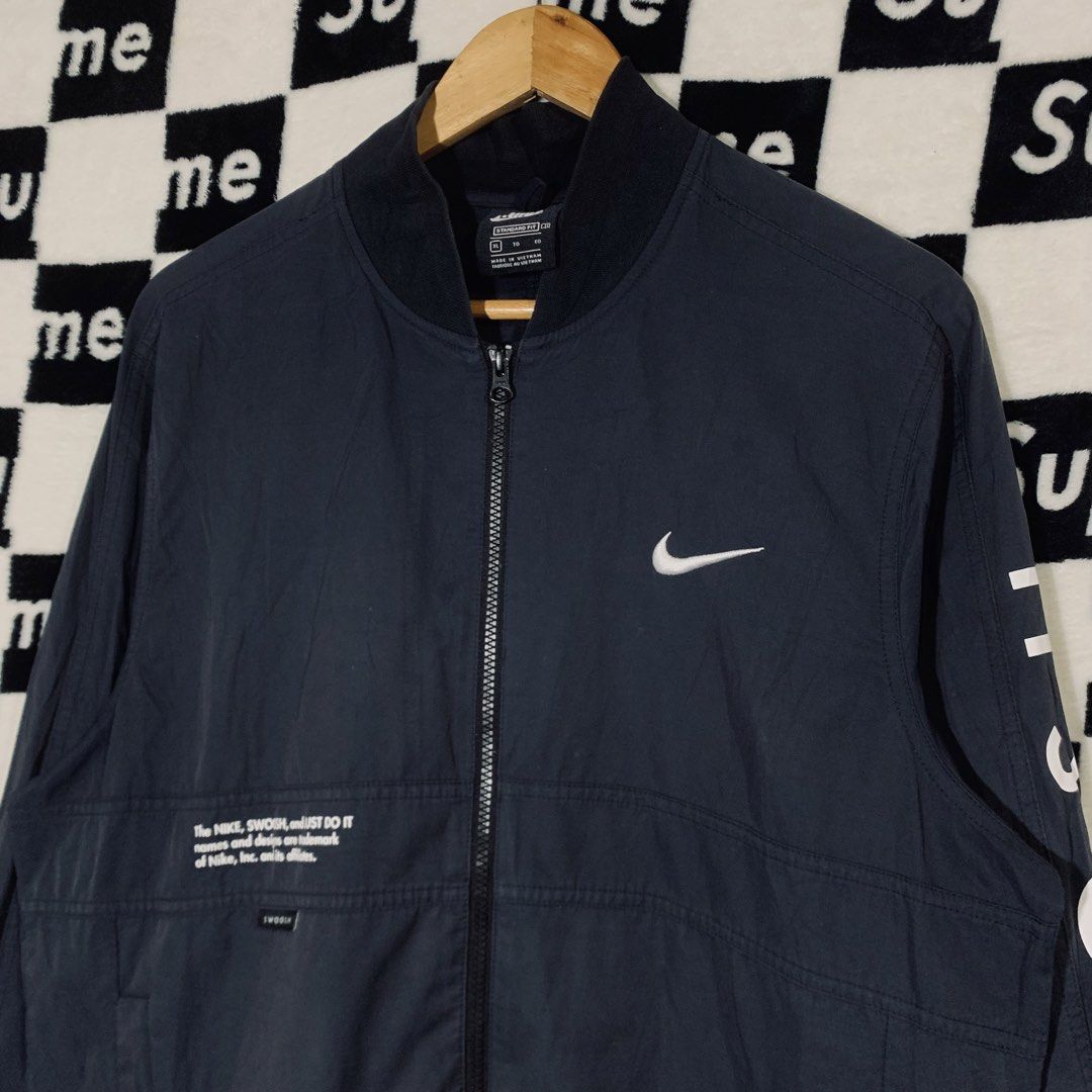 Nike Swoosh Bomber Jacket Navy Blue XL (Category: Coats, Jackets and Outerwear) located in Manila. Submitted by icemike444 (Listing ID 1470690959, Image 3). Description: - Brand: Nike - Style: Bomber jacket - Color: Dark navy blue - Size: XL (Standard fit) - Design: Full zip front, ribbed collar and cuffs - Details: Bold white Swoosh text down the left sleeve, trademark graphics on front right chest and large on upper back - Condition: Excellent 