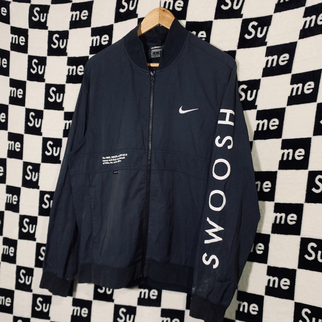 Nike Swoosh Bomber Jacket Navy Blue XL (Category: Coats, Jackets and Outerwear) located in Manila. Submitted by icemike444 (Listing ID 1470690959, Image 2). Description: - Brand: Nike - Style: Bomber jacket - Color: Dark navy blue - Size: XL (Standard fit) - Design: Full zip front, ribbed collar and cuffs - Details: Bold white Swoosh text down the left sleeve, trademark graphics on front right chest and large on upper back - Condition: Excellent 