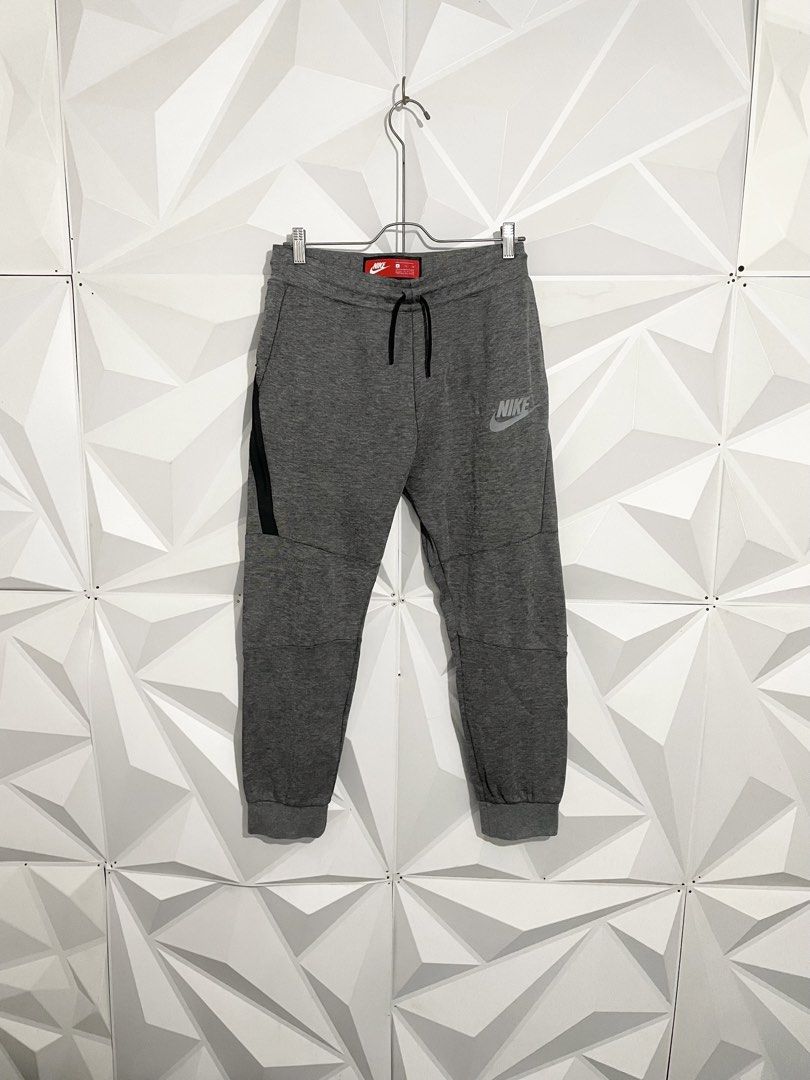 Nike Tech Fleece Grey Joggers Pants (Category: Joggers) located in Cabuyao City. Submitted by ParadisethriftedPh (Listing ID 1470648773, Image 1). Description: Cr: 9.8/10 Dimensions Waist: 30-34 Length: 35 - Authentic Nike Tech Fleece sweatpants in grey - Elastic waistband with dark grey adjustable drawstring - Signature black taped zipper pocket on the right leg - Reflective Nike logo near the left hip for visibility - Comfortable ribbed ankle c