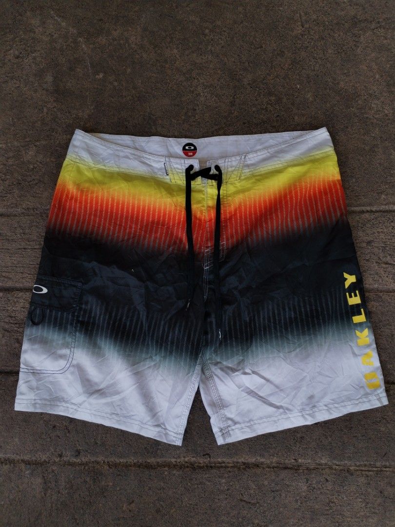 Oakley Gradient Surf Boardshorts Size 38 (Category: Swim Trunks & Board Shorts) located in Legazpi City. Submitted by justinbarcelon (Listing ID 1470683874, Image 1). Description: - Brand: Oakley - Size: 38 - Design: Gradient fading from yellow and red to black and white with bold left-leg branding - Material: 100% polyester - Features: Secure drawstring waist closure and a convenient side cargo pocket with the iconic Oakley ellipse logo - Ideal 