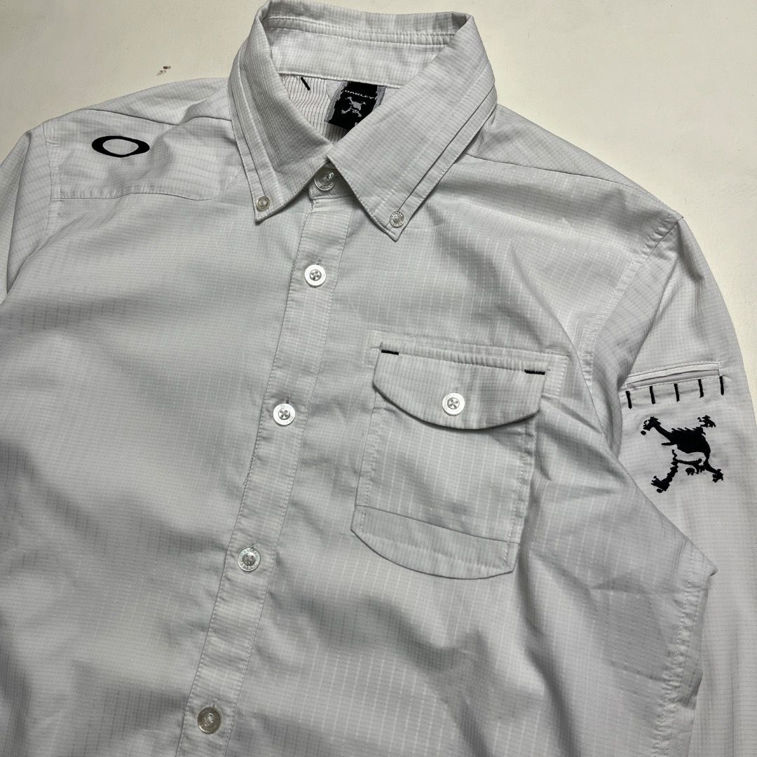 Oakley Software Button-Down Long Sleeve Shirt White Size L (Category: Coats, Jackets and Outerwear) located in Caloocan City. Submitted by achilles_grails (Listing ID 1470594198, Image 2). Description: White Oakley button-down shirt with a subtle grid pattern. Long sleeves, button-up front, collar with button downs. Single chest pocket with flap and button closure. Graphic embroidery on the left sleeve and Oakley branding on the right shoulder. B