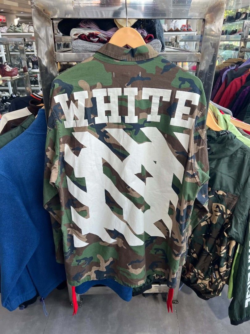 Off-White Camouflage Military Patch Jacket (Category: Coats, Jackets and Outerwear) located in Urdaneta. Submitted by jayceegarage (Listing ID 1470691646, Image 2). Description: - Brand: Off-White - Style: Camo military jacket with heavy streetwear branding - Design: Loaded with patches on both sleeves - Back Detail: Large white "WHITE" lettering and iconic arrow graphic - Pockets: Multiple functional front flap pockets - Closure: Classic button-