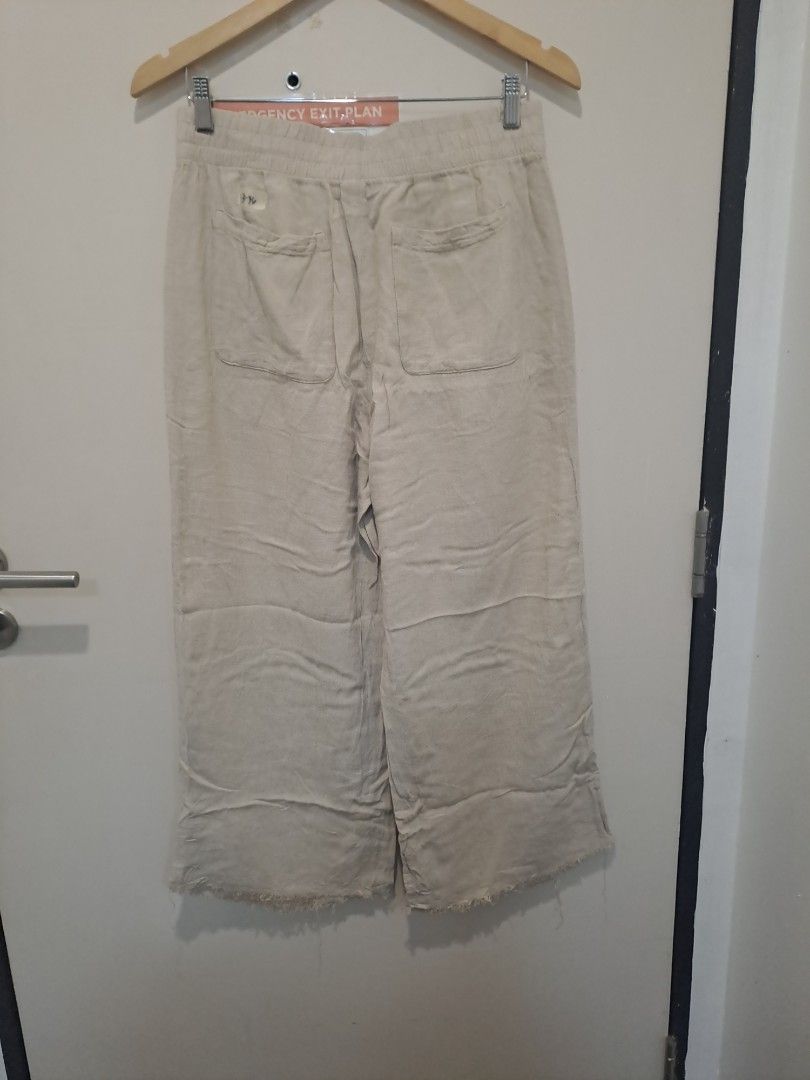 Old navy wide leg (Category: Other Bottoms) located in Manila. Submitted by joanbalde39643 (Listing ID 1470662052, Image 3). Description: The item in the image is a old navy pair of beige linen wide-leg cropped pants featuring an elastic smocked waistband, slip side pockets, and a casual frayed raw hem.