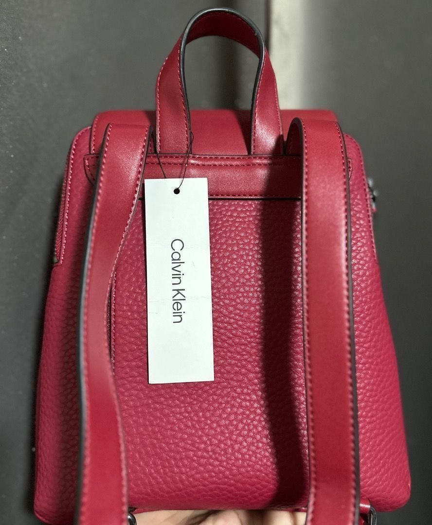 Original Calvin Klein Red Leather Backpack (Category: Backpacks) located in Pasig City. Submitted by holybeany.earth (Listing ID 1470594174, Image 3). Description: - Calvin Klein mini backpack - Flap closure - Front zip pocket - Top handle - Adjustable shoulder straps - Textured material - Calvin Klein logo on front.