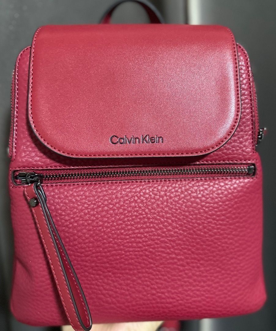 Original Calvin Klein Red Leather Backpack (Category: Backpacks) located in Pasig City. Submitted by holybeany.earth (Listing ID 1470594174, Image 1). Description: - Calvin Klein mini backpack - Flap closure - Front zip pocket - Top handle - Adjustable shoulder straps - Textured material - Calvin Klein logo on front.