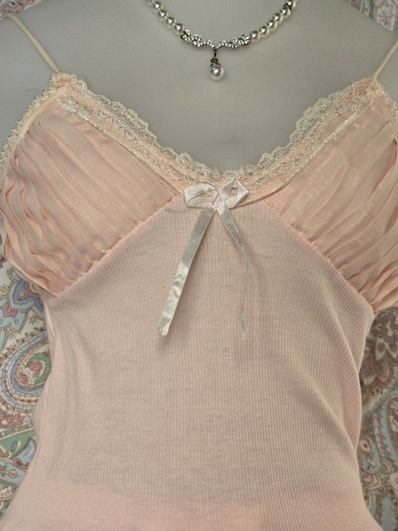 Pink camisole with lace trim (Category: Sleeveless) located in Dagupan City. Submitted by chislocker14 (Listing ID 1470598043, Image 2). Description: - Color: Soft pink - Material: Stretchy ribbed knit fabric - Design: Spaghetti straps, pleated bust with lace trim and white ribbon bow - Feature: Attached layered pink ruffled skirt at the hem - Style: Coquette / Y2K / Casual cute.