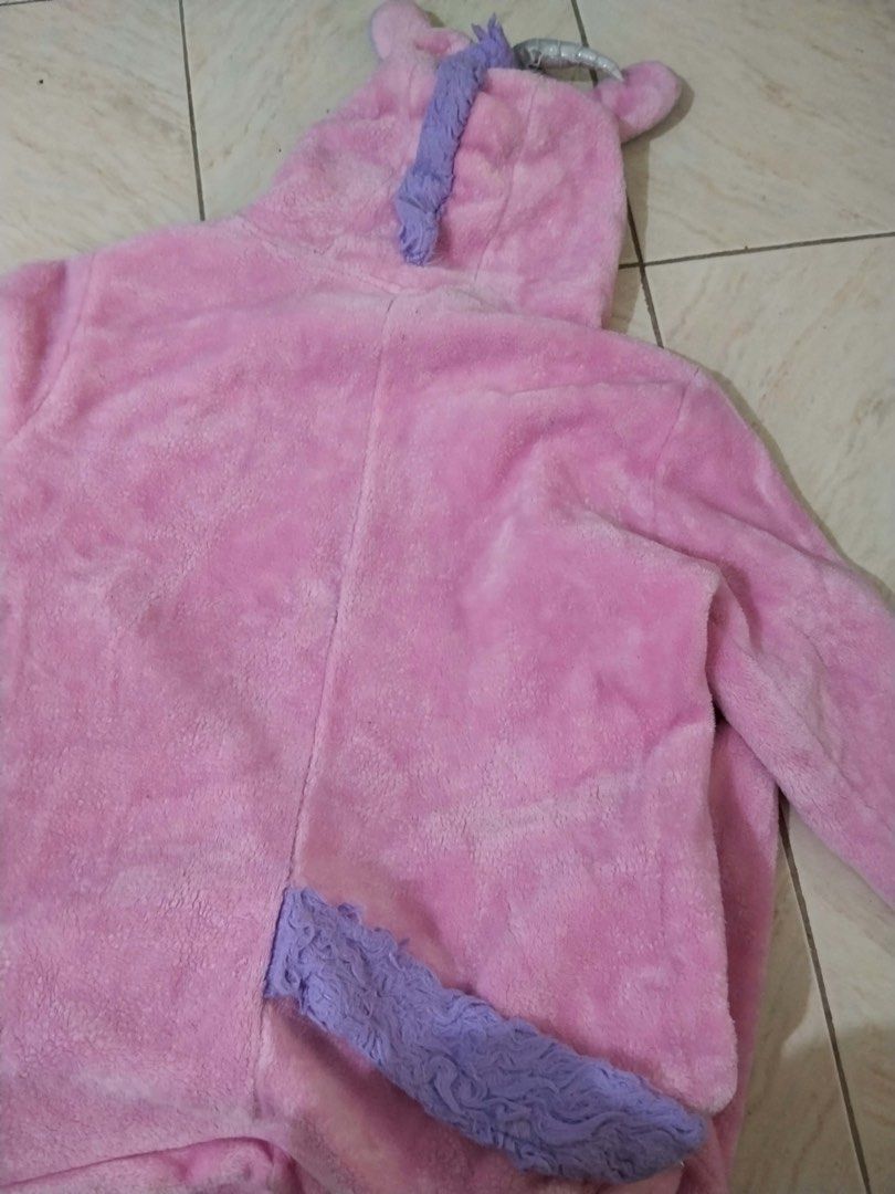 Pink Unicorn Onesie Pyjamas Costume (Category: Coats, Jackets and Outerwear) located in Calamba. Submitted by rhiajapansurplus-babystuff-03 (Listing ID 1470619352, Image 3). Description: - Fluffy pink and white unicorn onesie - Super soft, warm plush material ideal for lounging or costumes - Features a hood with cute ears, horn, and mane, plus a purple tail and cuffs - Convenient zip-up front closure - Flaw: Small stain on the left chest area nea