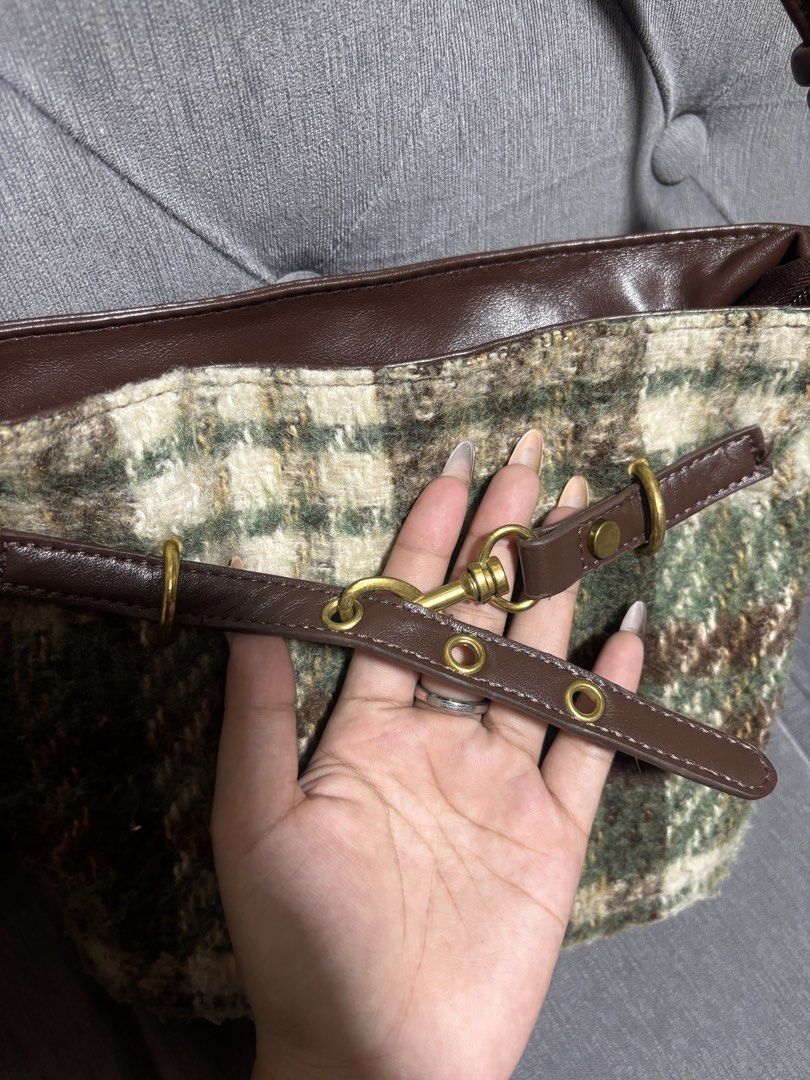 Plaid and Brown Leather Shoulder Bag (Category: Shoulder Bags) located in Manila. Submitted by alyanarein (Listing ID 1470723575, Image 2). Description: Green and brown plaid tweed shoulder bag with smooth brown faux leather trim. Thrifted. Used only once. Zipper closure on top with brown fabric lining inside. Dual strap design featuring knotted details and metal hardware. Adjustable. Decorative strap across the front with clasp and grommet accen