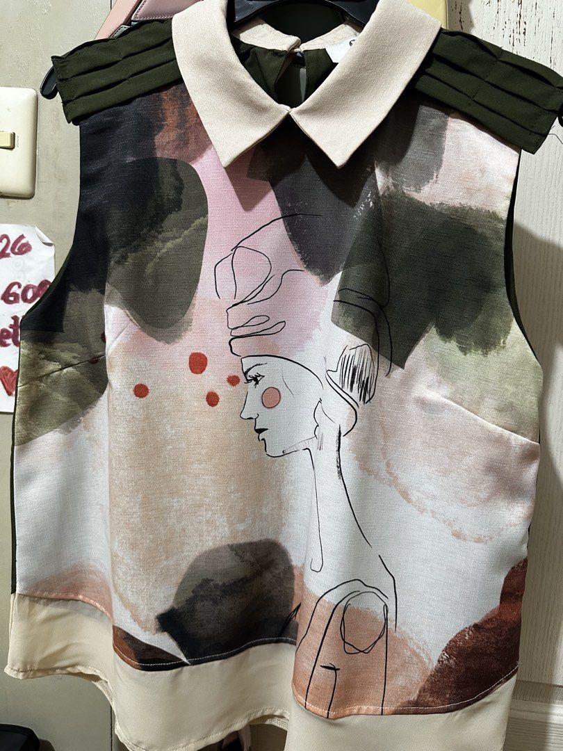 Plains & Prints Abstract Face Print Sleeveless Collared Top (Category: Sleeveless) located in Balanga. Submitted by jamilbeauty5 (Listing ID 1470673587, Image 2). Description: - Brand: Plains & Prints - Size: PHL / UK 12 / US 8 - Design: Colorful abstract face print with contrast cream collar and dark green pleated shoulders - Closure: Back neck button - Fabric: Lightweight with a fluid drape - Care Instructions: 40°C wash with separate colors, l