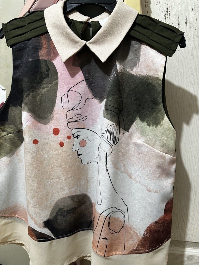 Plains & Prints Abstract Face Print Sleeveless Collared Top (Category: Sleeveless) located in Balanga. Submitted by jamilbeauty5 (Listing ID 1470673587, Image 1). Description: - Brand: Plains & Prints - Size: PHL / UK 12 / US 8 - Design: Colorful abstract face print with contrast cream collar and dark green pleated shoulders - Closure: Back neck button - Fabric: Lightweight with a fluid drape - Care Instructions: 40°C wash with separate colors, l