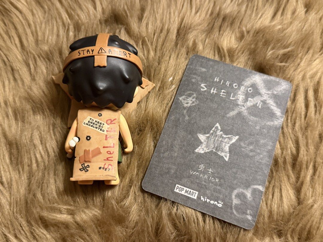 Pop Mart Hirono Shelter Warrior Figure (Category: Designer & Blind Box Toys) located in Mandaluyong City. Submitted by knb.ph (Listing ID 1470670253, Image 2). Description: - Pop Mart Hirono Shelter Series - Warrior - Figure with cardboard star costume, small bone accessory, and character card - Sturdy vinyl material with detailed paintwork including 'Stay Alert' and 'Keep Out' markings - Brand new / opened to check design only.