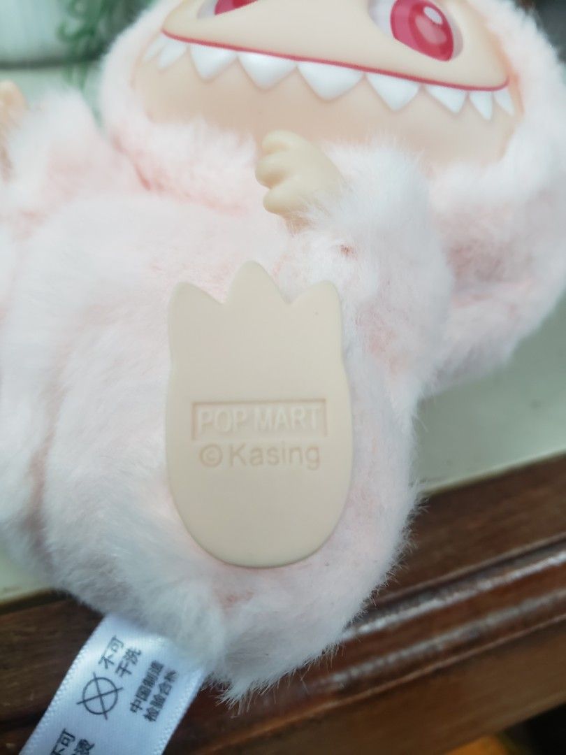 Pop Mart The Monsters Kasing Labubu Plush (Category: Plushies & Soft Toys) located in Pagsanghan. Submitted by yuchinz (Listing ID 1470661831, Image 2). Description: - Authentic Pop Mart The Monsters plush figure by Kasing - Adorable pink fur with signature plastic face, big red eyes, and pointy teeth - Includes attached key ring with branded logo ribbon - Official Pop Mart and Kasing stamp on the foot - Original care instructions and material ta