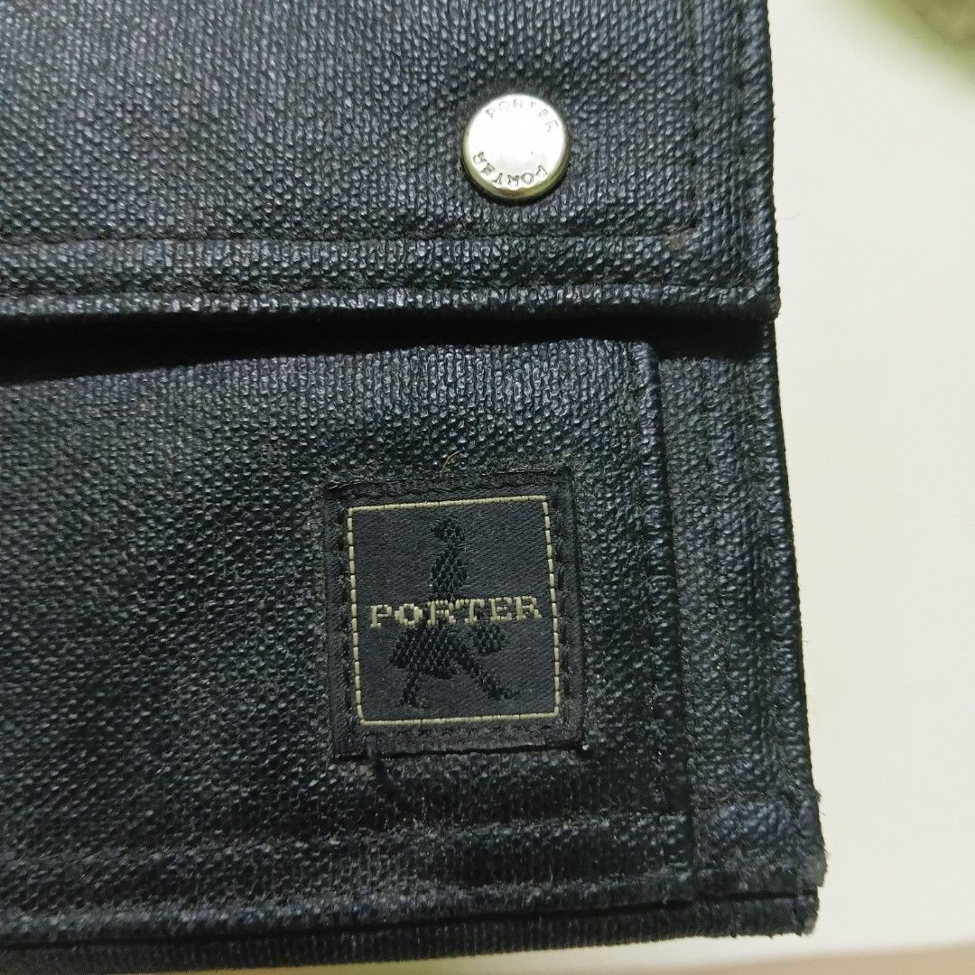 Porter International black trifold canvas wallet (Category: Wallets & Card Holders) located in Manila. Submitted by daphnefinds (Listing ID 1470641436, Image 3). Description: Porter International trifold wallet in black canvas texture. Front flap secured with two metal snap buttons and iconic Porter woven brand patch. Interior contains multiple card slots, clear ID window, and zipper compartment. Key ring attached at the bottom exterior. Durable 