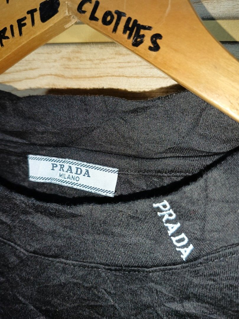 Prada Black Long Sleeve Sweater with Logo Patch (Category: Coats, Jackets and Outerwear) located in Narra. Submitted by rhyanguan63087 (Listing ID 1470628655, Image 3). Description: - Brand: Prada - Color: Black - Material: Soft, comfortable cotton - Design: Crew neckline with subtle collar embroidery - Logo: Signature light blue triangle metal logo patch on the left chest - Details: Prada Milano inner tag and care label - Condition: Clean and re