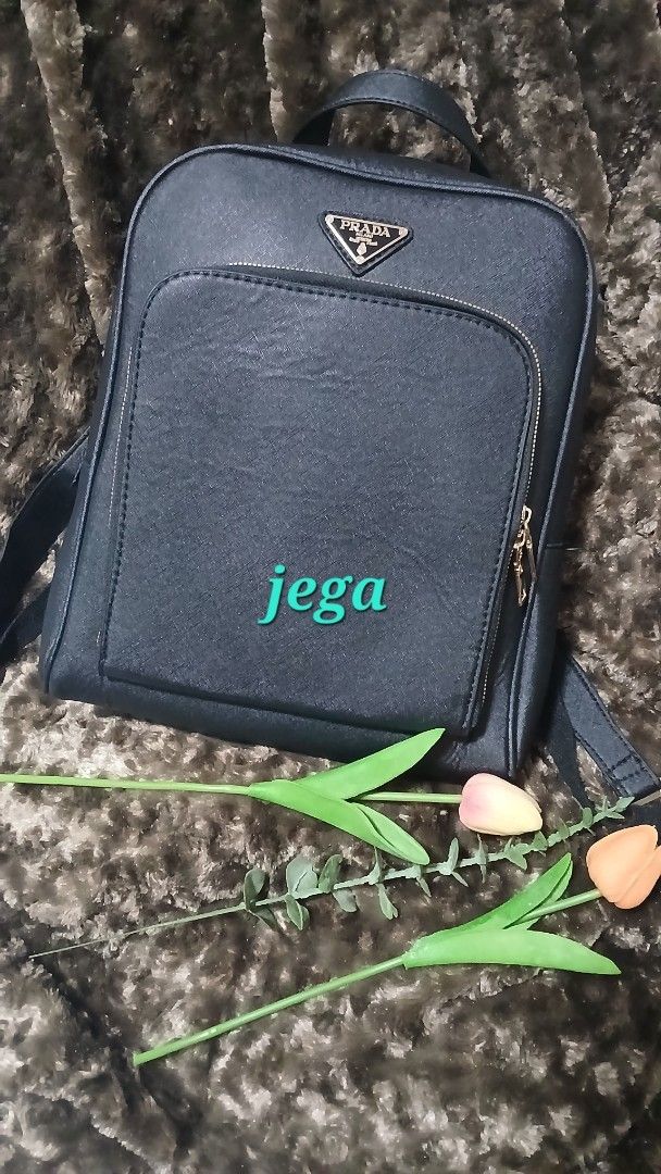 Prada Black Saffiano Leather Backpack (Category: Backpacks) located in Taguig. Submitted by jegadablo (Listing ID 1470741004, Image 1). Description: - Material: Saffiano leather texture in classic black - Hardware: Premium gold-tone accents - Design: Structured shape with a clean silhouette and iconic triangular logo plaque - Storage: Large front zippered pocket - Comfort: Top grab handle and adjustable shoulder straps.
