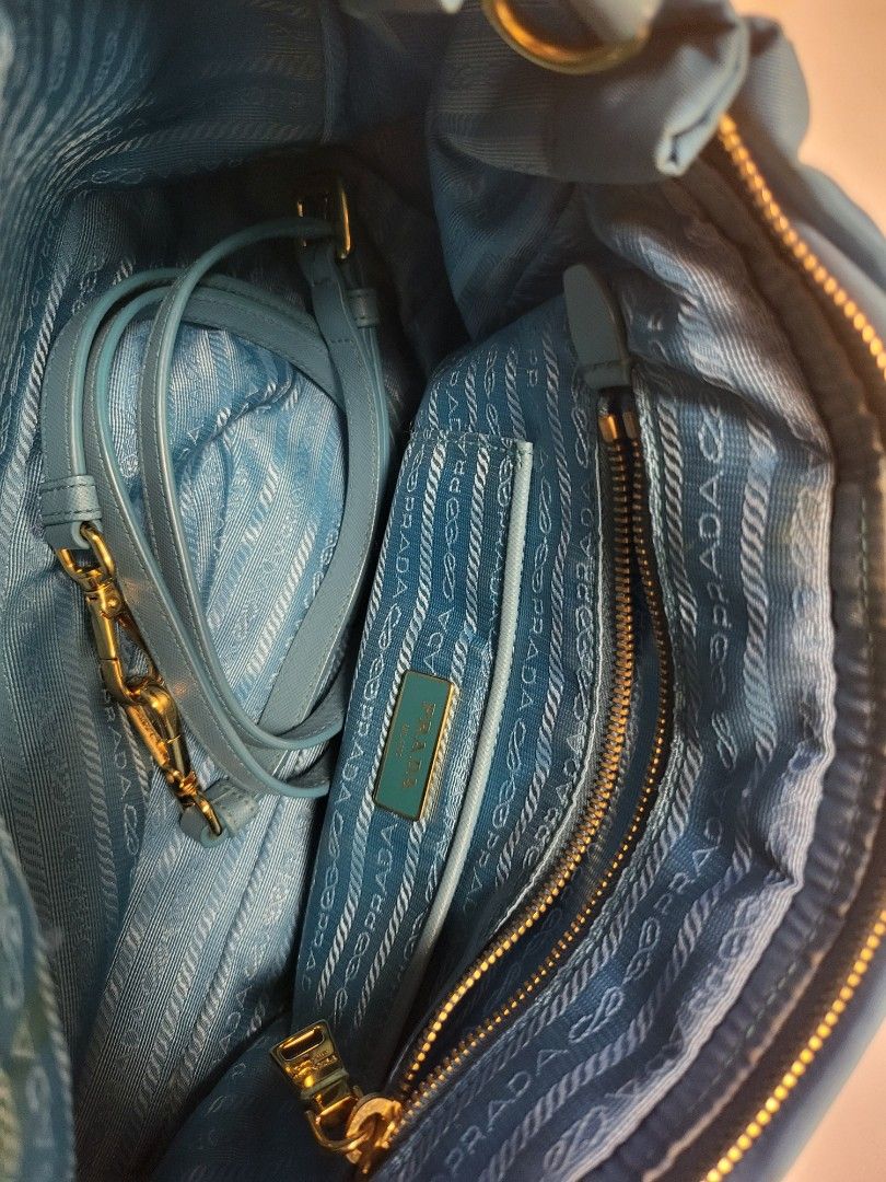 Prada Blue Nylon Tote Bag with Strap (Category: Luxury Bags & Wallets) located in Pasig City. Submitted by angel025 (Listing ID 1470606382, Image 2). Description: - Brand: Prada - Color: Light Blue - Material: Classic Prada nylon with gold-tone hardware - Exterior: Front zipped pocket featuring the iconic triangular logo plaque - Strap: Includes a detachable matching shoulder strap - Interior: Prada logo-lined fabric with a zipped compartment and