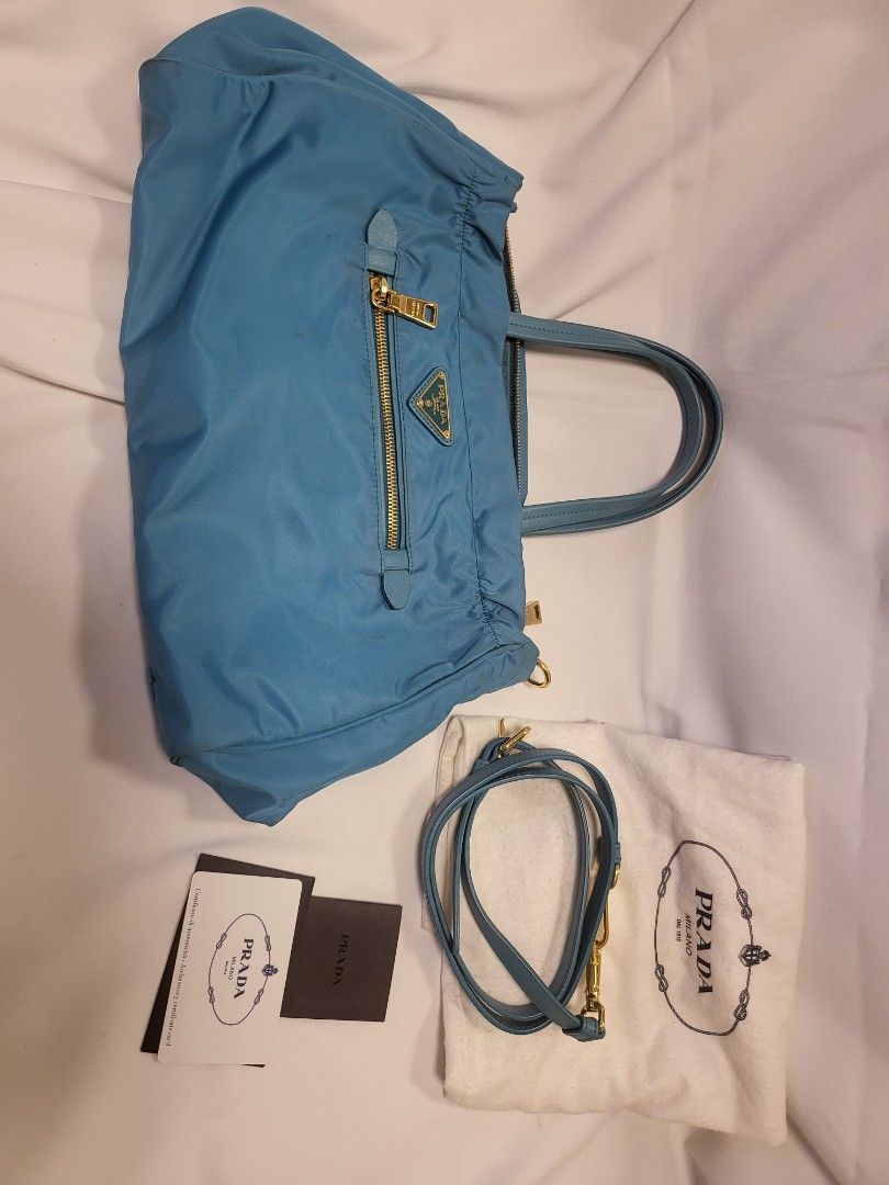 Prada Blue Nylon Tote Bag with Strap (Category: Luxury Bags & Wallets) located in Pasig City. Submitted by angel025 (Listing ID 1470606382, Image 1). Description: - Brand: Prada - Color: Light Blue - Material: Classic Prada nylon with gold-tone hardware - Exterior: Front zipped pocket featuring the iconic triangular logo plaque - Strap: Includes a detachable matching shoulder strap - Interior: Prada logo-lined fabric with a zipped compartment and
