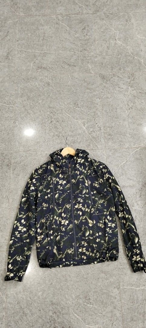 Prada Milano Floral Print Hooded Jacket (Category: Coats, Jackets and Outerwear) located in Bacolod City. Submitted by hurleydediamante0513 (Listing ID 1470589245, Image 1). Description: - Brand: Prada Milano - Style: Lightweight hooded windbreaker / layering jacket - Color: Dark blue with all-over floral and leaf pattern - Hardware: Premium Riri zippers with branded metal pulls - Features: Drawstring hood and functional chest utility pockets - C